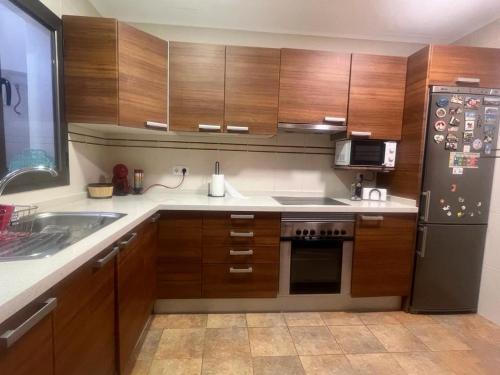 a kitchen with wooden cabinets and a black refrigerator at Casa vacacional Renacer in Gran Tarajal