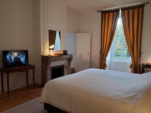 a bedroom with a white bed and a fireplace at Logis des Tourelles in Cognac