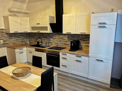 uma cozinha com armários brancos e uma mesa de madeira com mesa; em Cozy Apartment Bernburg 1 em Roschwitz