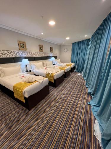 a row of beds in a hotel room with blue drapes at فندق الميقات أجياد in Mecca