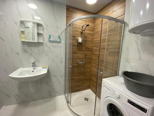 a bathroom with a shower and a sink and a washing machine at Green Paradise Complex in Primorsko