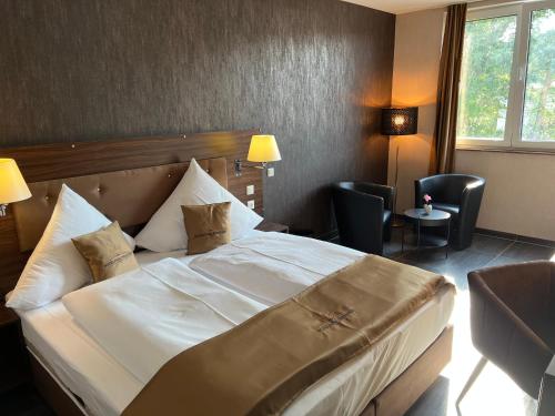 um quarto de hotel com uma grande cama branca e cadeiras em Hotel Pasa Paradies KOSTENLOSE PARKPLÄTZE em Hanau am Main