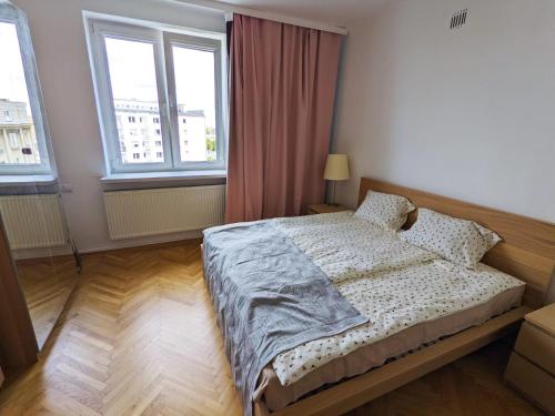 een slaapkamer met een bed en 2 ramen bij Comfortable and quiet flat in Central Warsaw in Warschau