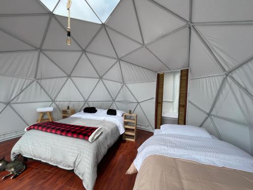 two beds in a room with a triangular wall at Glamping Wayra in Guatavita