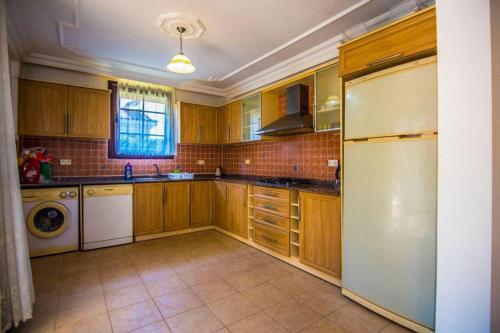 a kitchen with wooden cabinets and a white refrigerator at Villa Mor Fethiye in Fethiye