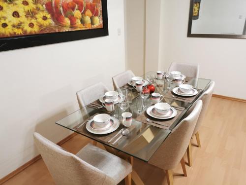 a dining room table with chairs and a painting at Departamento Miraflores del Jardín. in Cajamarca