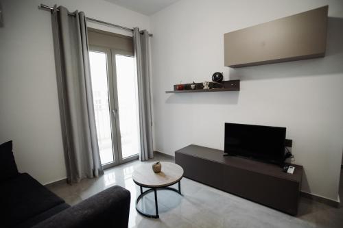 Una sala de estar con un sofá, un televisor y una mesa. en Olympia apartments Heraklion center, en Heraclión
