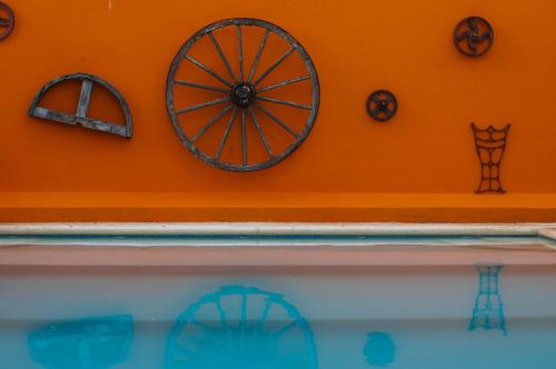 an orange wall with a wooden wheel on it at Casa Xcanatun in Mérida