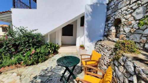 a patio with chairs and a table and a stone wall at Syraino in Kolios