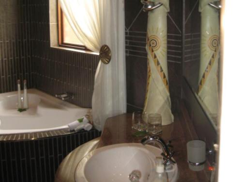 a bathroom with a sink and a bath tub at Witwater Guest House & Spa in Kempton Park