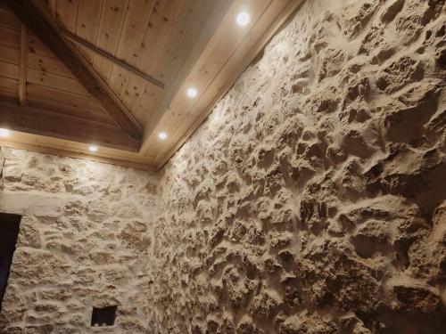 a stone wall in a room with a wooden ceiling at Once upon a rock in Pythagoreio