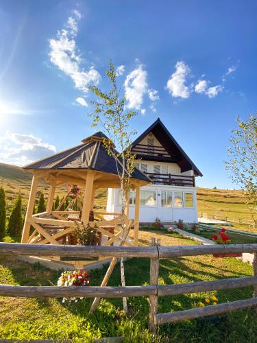 a house with a wooden gazebo in a field at Guest House SARA in Žabljak