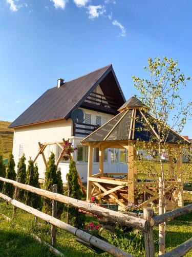 a house with a wooden fence in front of it at Guest House SARA in Žabljak