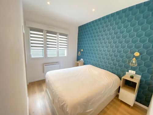 - une chambre avec un lit blanc et un mur bleu dans l'établissement Le Sacré - CENTRE - Cour privative - PARKING, à Reims