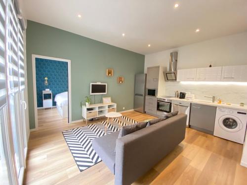 a living room with a couch and a kitchen at Le Sacré - CENTRE - Cour privative - PARKING in Reims