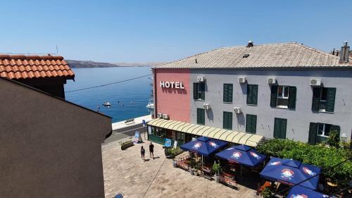 a view of a building with people walking in front of the water at Apartments ANA Karlobag in Karlobag