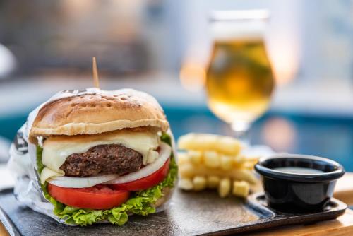 a hamburger on a tray with a glass of beer at Hotel Elite in Barrancabermeja