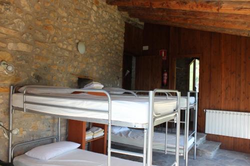a room with two bunk beds in a stone wall at Albergue Casa Fumenal in Padarniu