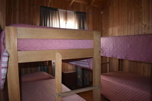 two bunk beds in a room with purple sheets at Cabaña Los Maquis in Licán Ray