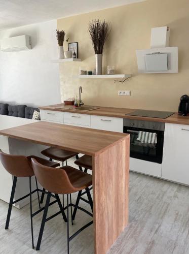 uma cozinha com uma mesa de madeira e cadeiras em Sunny apartment on the lakes em Senec