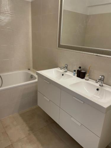 a bathroom with two sinks and a bath tub at Sunny apartment on the lakes in Senec