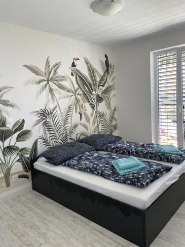 1 dormitorio con 1 cama con un mural de palmeras en Sunny apartment on the lakes, en Senec
