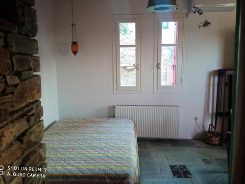 ein Schlafzimmer mit einem Bett und zwei Fenstern in der Unterkunft ArtHome0B in Panormos