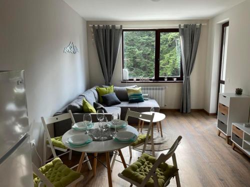 a living room with a table and a couch at Pine Tree Apartment / Borovets Gardens in Borovets