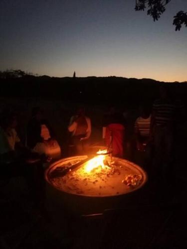 a group of people sitting around a fire in the dark at HomeSweetHome Farm Cottage in Nelspruit