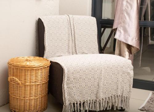 a blanket on a chair next to a basket at HomeSweetHome Farm Cottage in Nelspruit