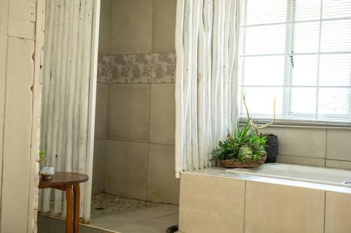 a bathroom with a tub and a window with a plant at HomeSweetHome Farm Cottage in Nelspruit