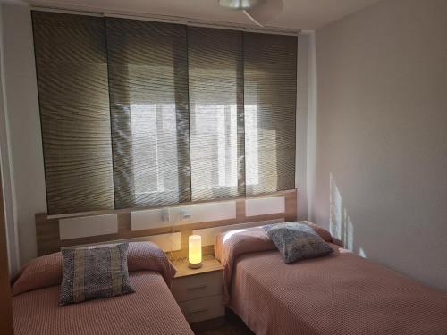 a bedroom with two beds and a window with blinds at apartamento Gandiazar 4 playa, VT-52979-V in Playa de Gandia