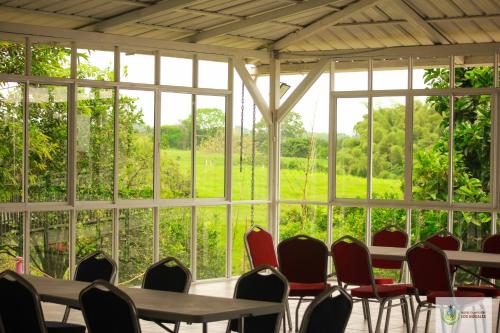 a room with tables and chairs in front of windows at Finca Hotel los Nogales in Quimbaya