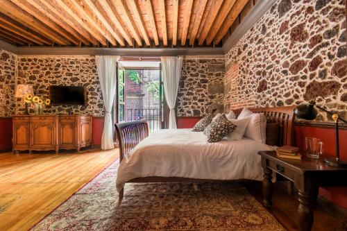 sypialnia z łóżkiem i kamienną ścianą w obiekcie CASA SAUTO SUITE CON BALCON w mieście Meksyk