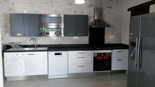 uma cozinha com armários brancos e um frigorífico de aço inoxidável em Gîte Dodo Lé La em Saint-Aignan