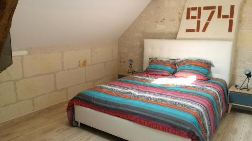 um quarto com uma cama com um cobertor colorido em Gîte Dodo Lé La em Saint-Aignan