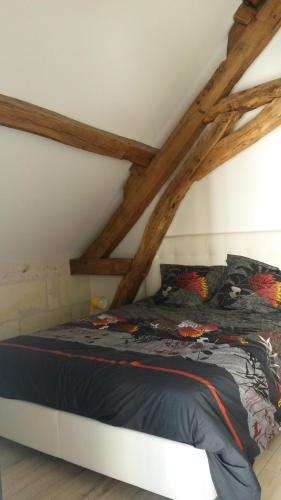 uma cama num quarto com vigas de madeira em Gîte Dodo Lé La em Saint-Aignan
