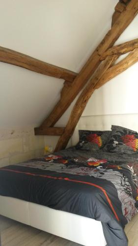łóżko w pokoju z drewnianymi belkami w obiekcie Gîte Dodo Lé La w mieście Saint-Aignan