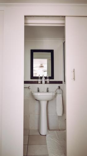a white bathroom with a sink and a mirror at Beside Still Waters Boutique Hotel in Durban