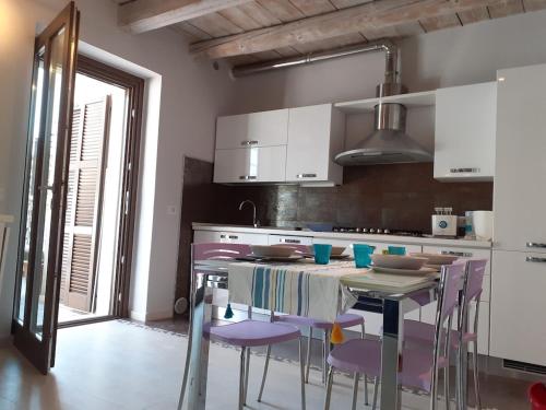 a kitchen with purple chairs and a table in a kitchen at Bouganville House in Senigallia