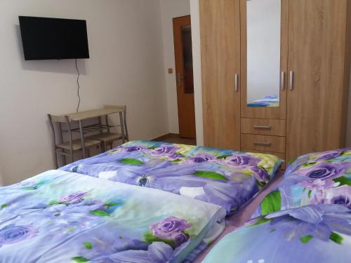 two beds in a room with purple flowers on them at Apartmány Na Valše in Sušice