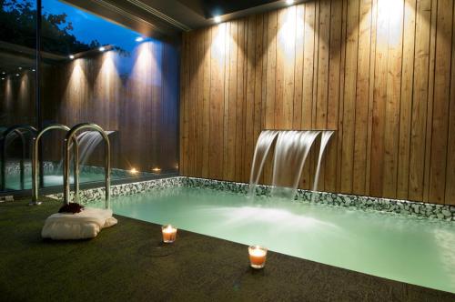 baño con piscina con fuente y velas en Hotel Terra Bonansa en Bonansa