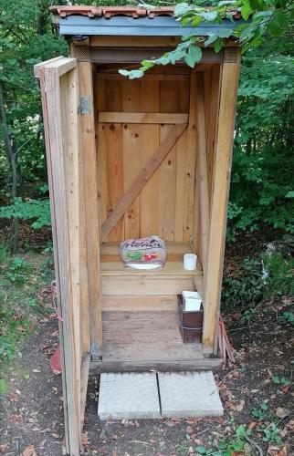 a wooden outhouse with a door in the woods at Natural Cottage Glamping Eco-Tiny House in Škocjan