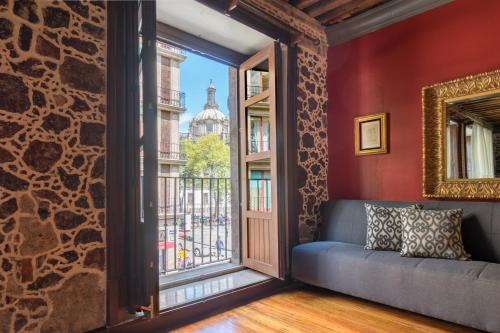 a room with a couch and a window with a view of a building at Historic Suite w balconies to Cathedral & Rooftop CASA SAUTO 5 in Mexico City