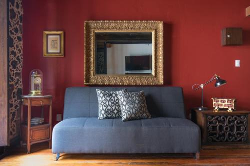 a blue couch in a red room with a mirror at Historic Suite w balconies to Cathedral & Rooftop CASA SAUTO 5 in Mexico City