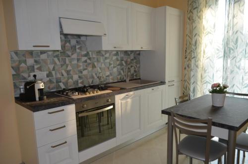 una cucina con mobili bianchi, un tavolo e un bancone di Raggio di Sole a Gaeta