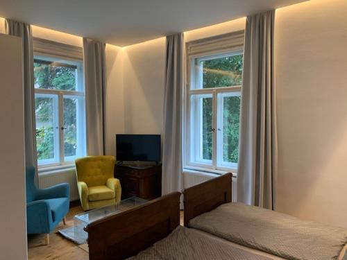 a bedroom with a bed and a chair and windows at Vila Bohemia Saxon Switzerland & SPA in Šluknov