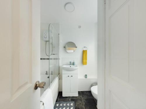 Baño blanco con lavabo y aseo en 247 Serviced Accommodation in Telford- 3BR HOUSE en Telford