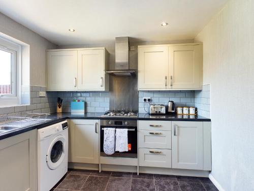 a kitchen with white cabinets and a stove top oven at 247 Serviced Accommodation in Telford- 3BR HOUSE in Telford