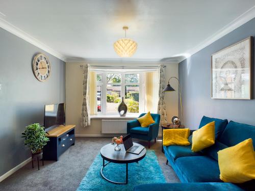 a living room with a blue couch and yellow pillows at 247 Serviced Accommodation in Telford- 3BR HOUSE in Telford